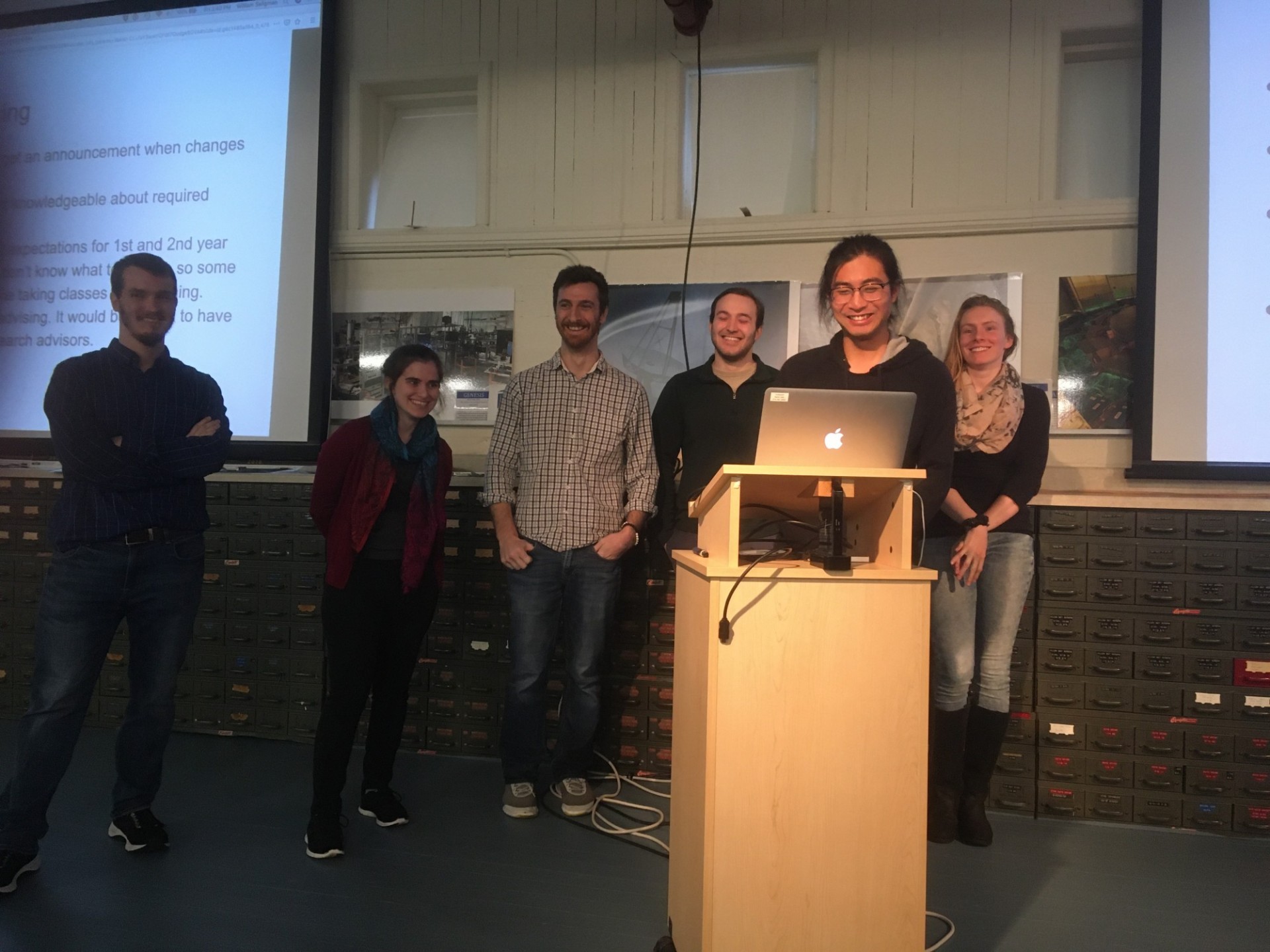 6 students talking behind a podium 